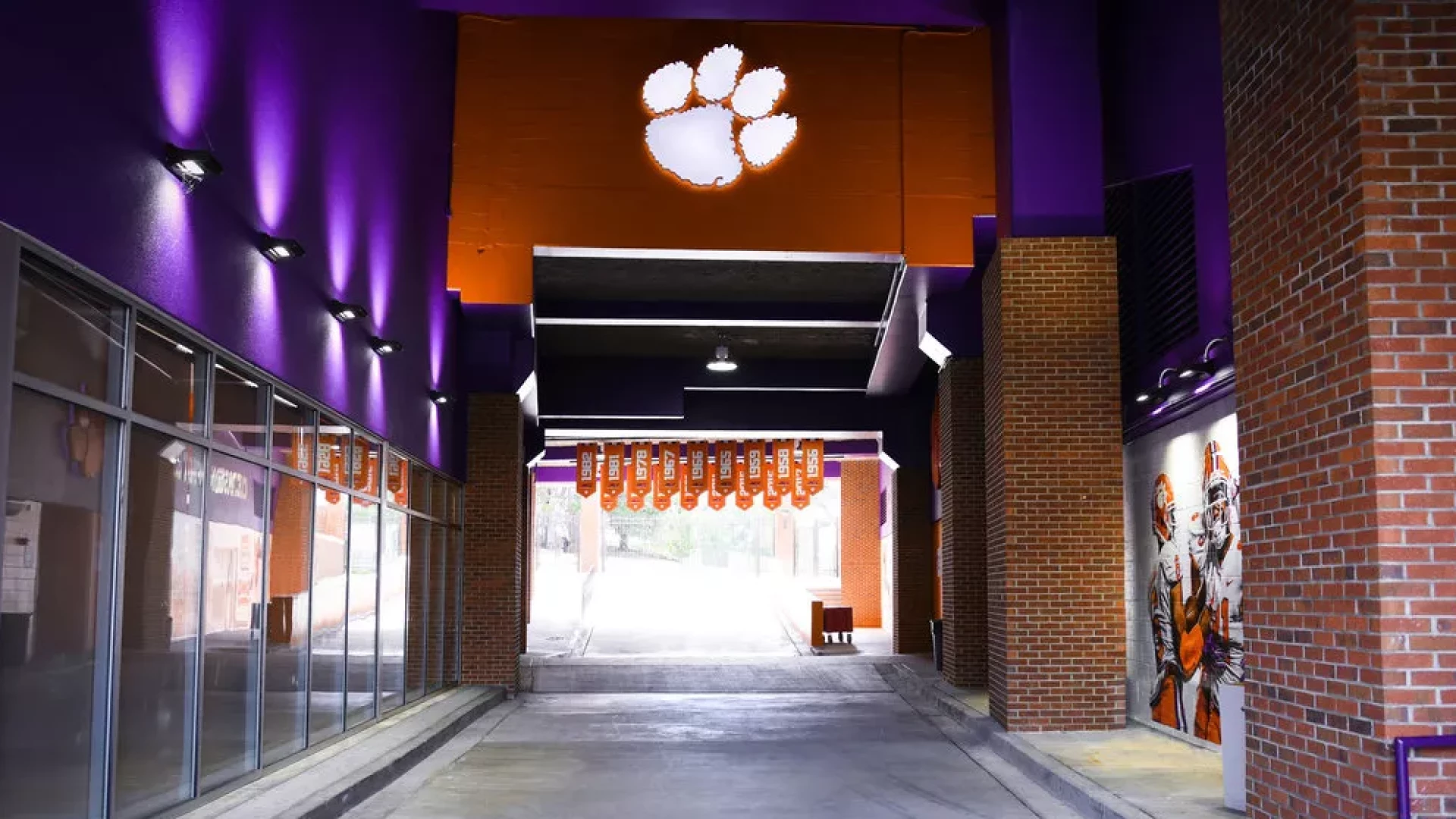 Clemson players tunnel with illuminated logo and banners.